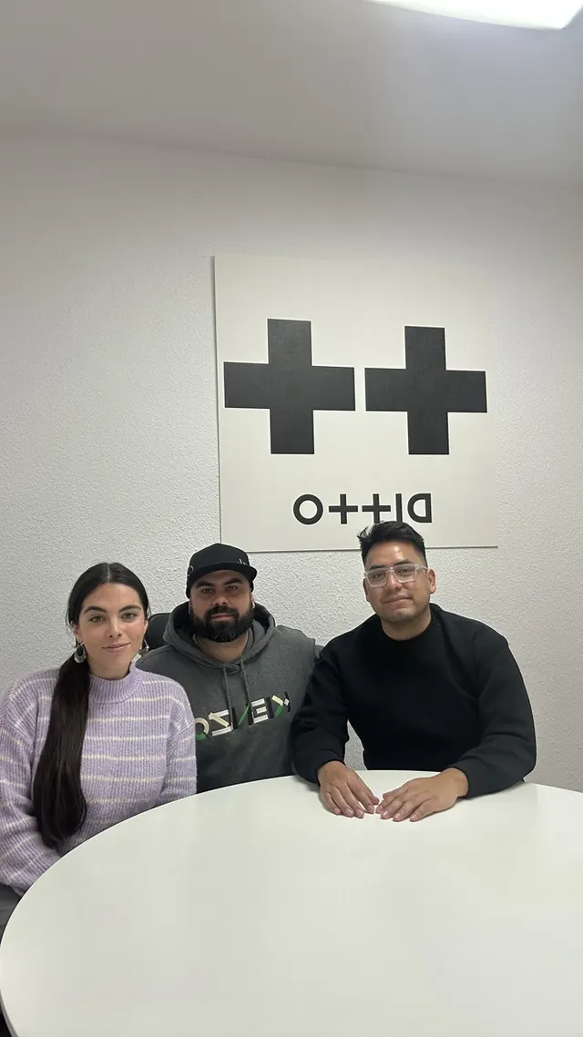 Macuto con dos personas de Ditto Music en su oficina de España, bajo el logotipo de Ditto