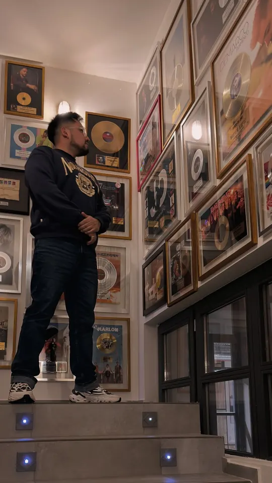 Macuto en Warner Music España, ante una pared de discos enmarcados